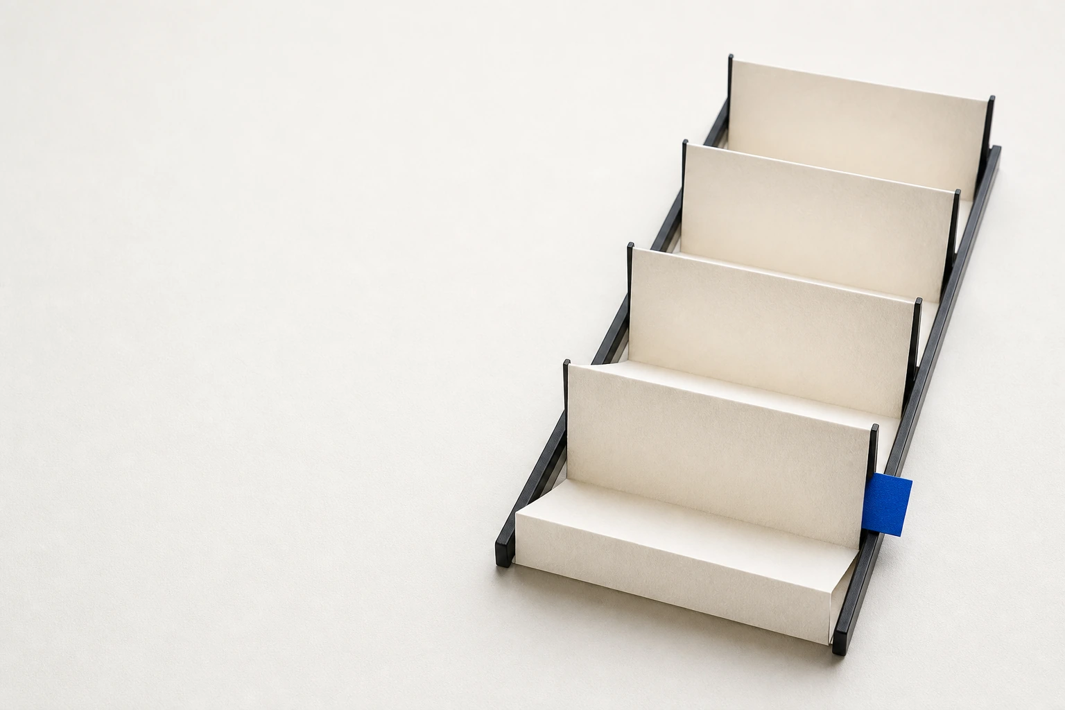 A continuous accordion-fold paper sequence held by guide rails with a cobalt learning tab.